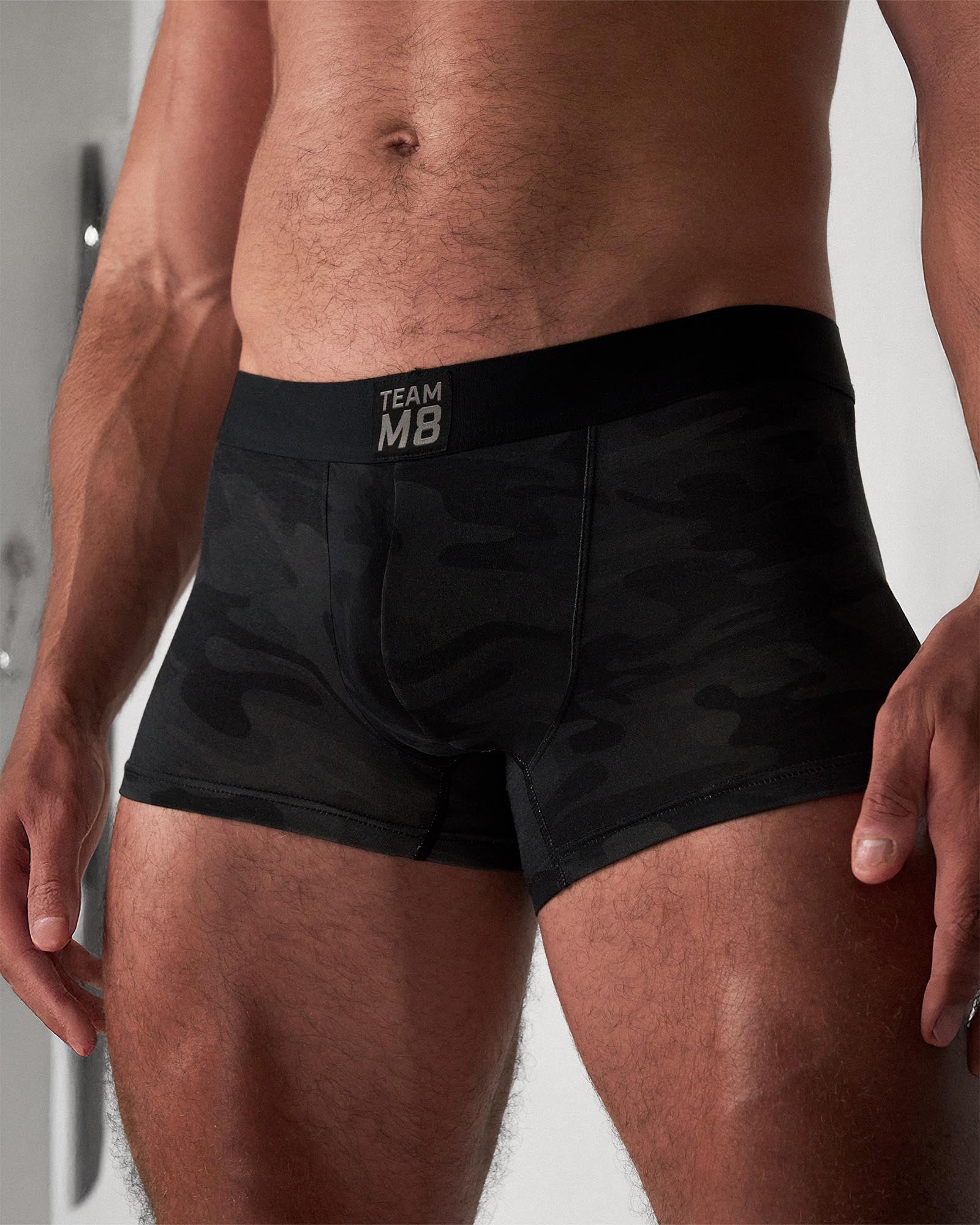 Black boxer briefs with 'TEAM MB' label worn by a person on a neutral background